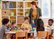 Children with their teacher in an EYFS classroom. Play matters just as much as learning in one.