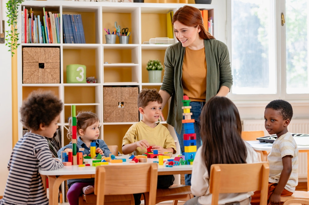Children with their teacher in an EYFS classroom. Play matters just as much as learning in one.